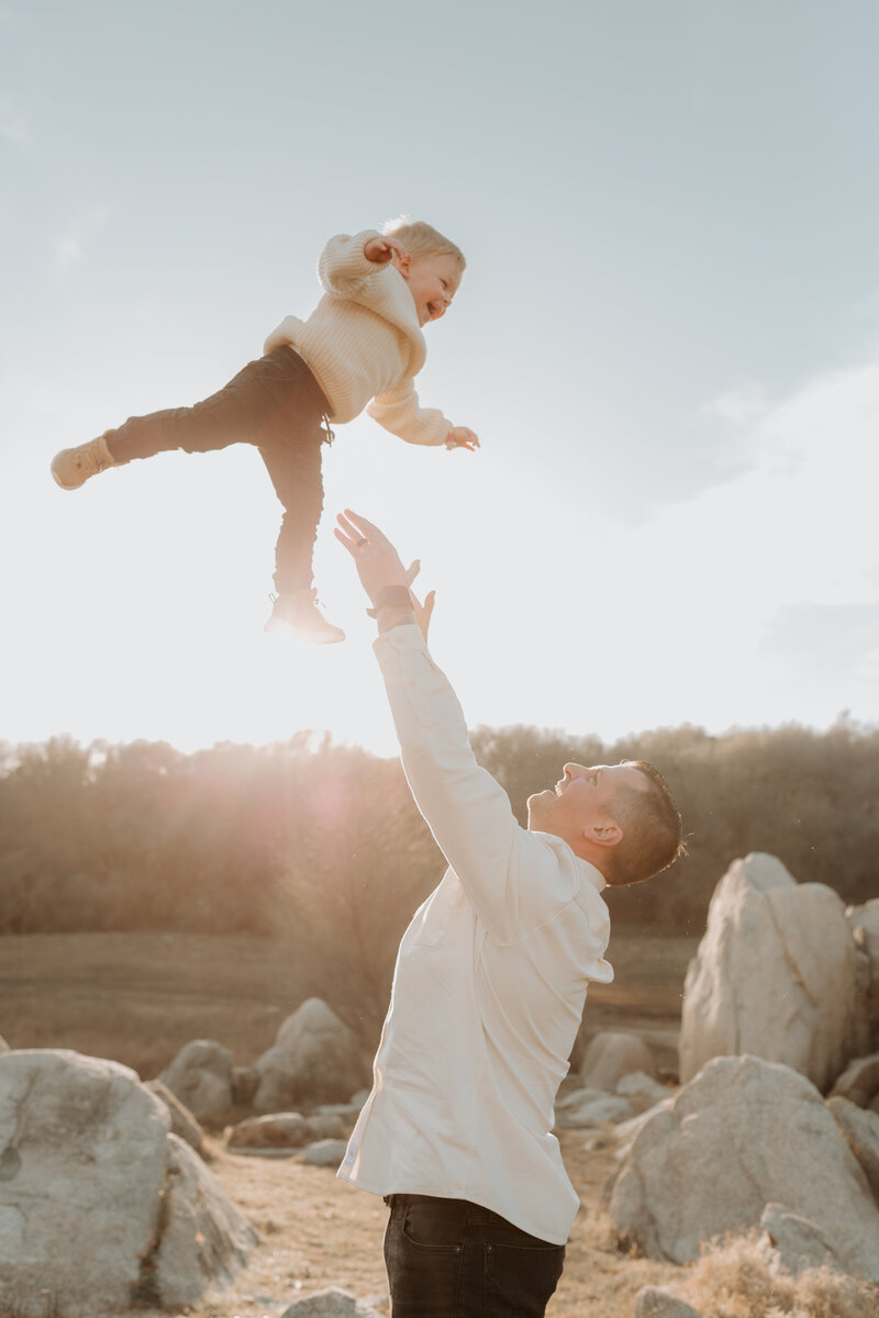 A woman holding a baby in a field at sunset.
