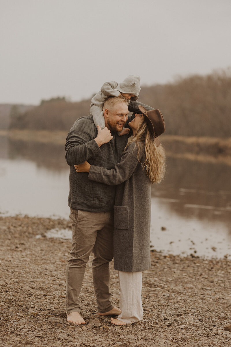 Minneapolis photographer smiles up at her baby as he sits on her husband's shoulders