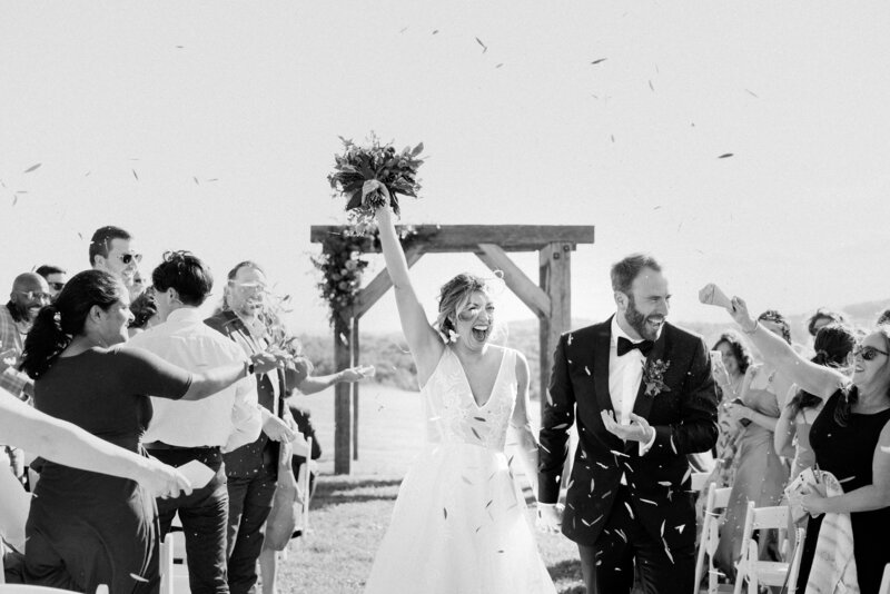 black and white photo of bride and groom walking back down the aisle after getting married
