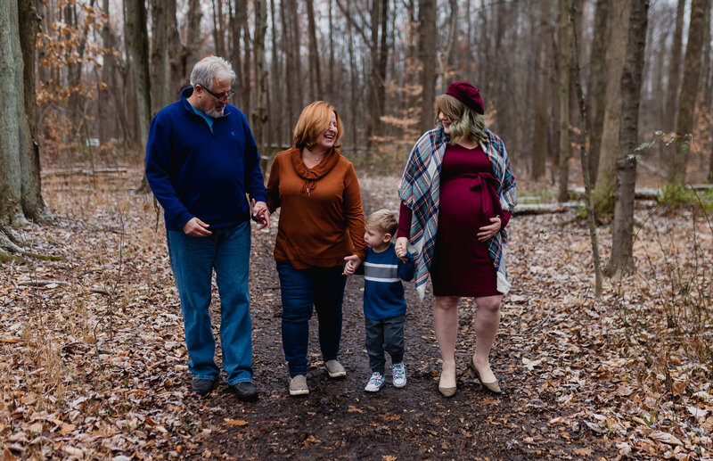 Family photographer capturing a grandfather, grandmother, young mom, and child walking outside.