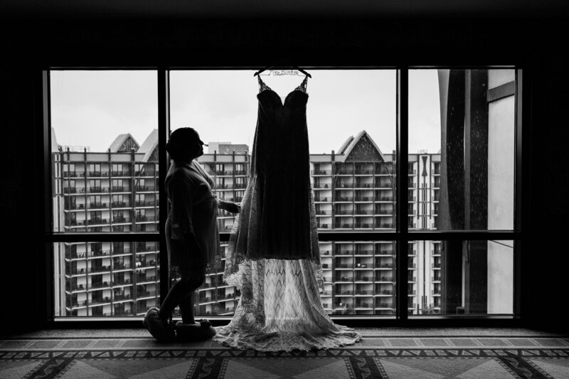 Black and white photo of bride looking at dress in window at Disney
