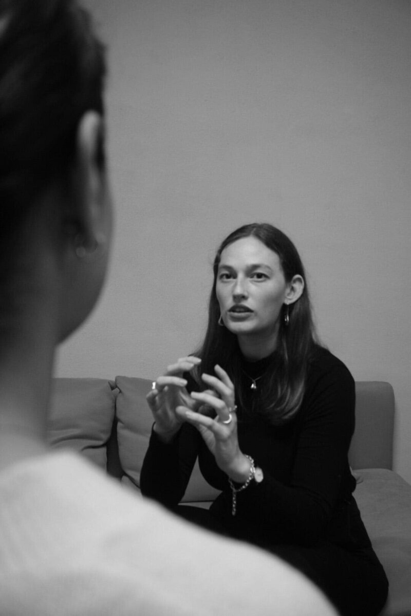 Cora Demary speaking to a small group in a casual setting.