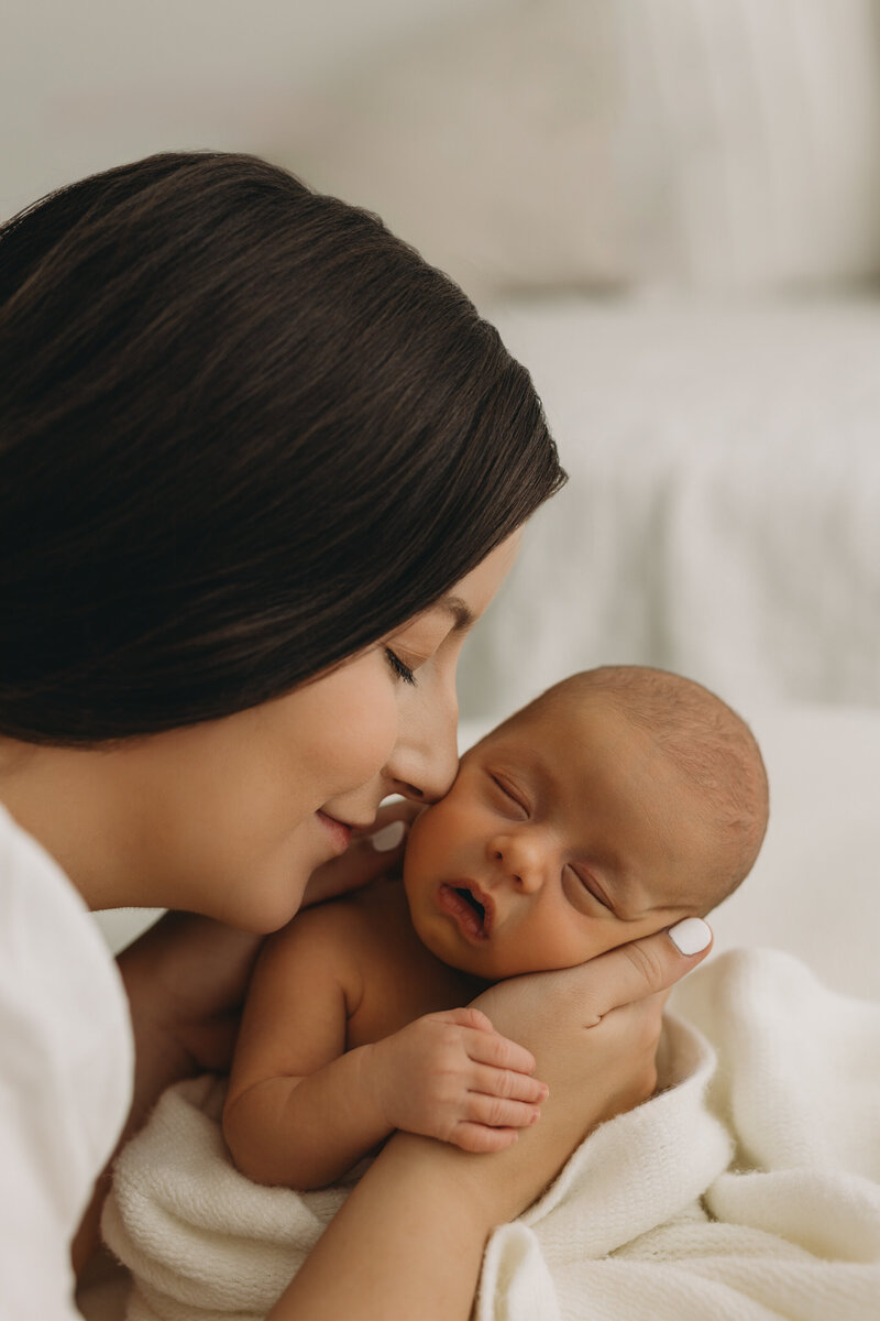 Newborn Portraits taken in Kelowna BC studio with dad holding baby in his hands and he has tatoos all over his hands and arms