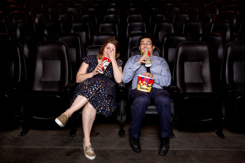 A couple sitting in a movie theater drinking soda.