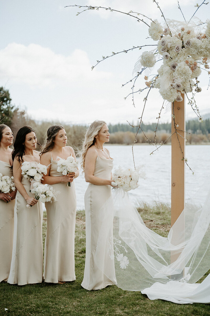 Close-up of asymmetrical floral installation with white hydrangea, mauve and sand garden roses, budding branches, and bleached fern on a wooden arbor at Black Butte Ranch, by Summer Robbins Flowers