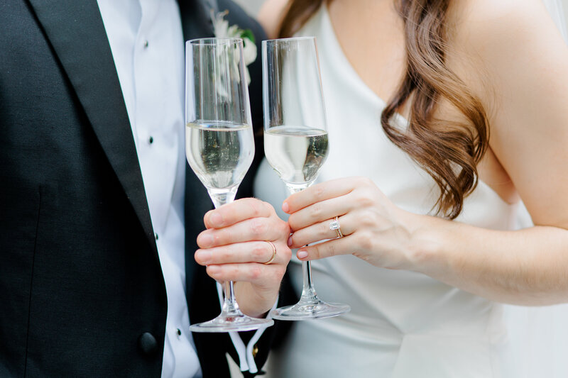 Close-up photo of bride and groom holding champagne glasses