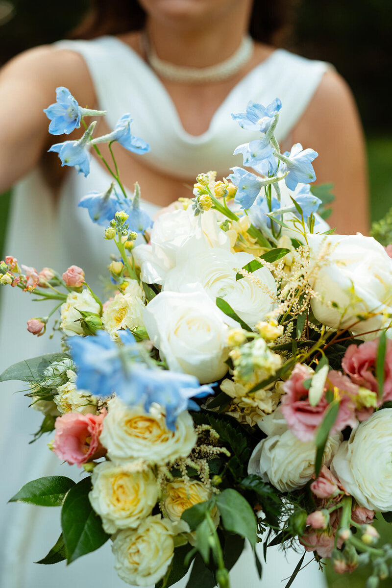 Close up of bride's wedding bouquet with baby blue, pink, and white flowers