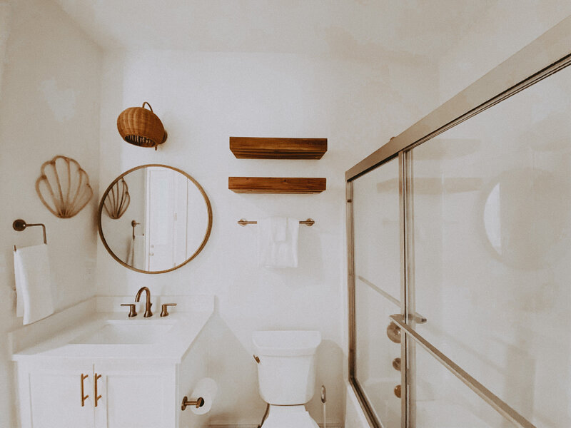 white bathroom with wooden round mirror