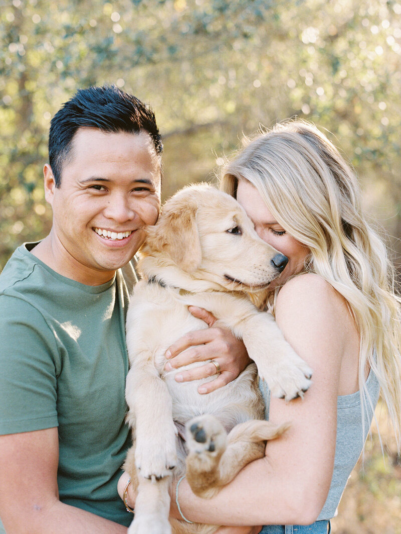 a film image of a couple cuddling with their puppy and embracing