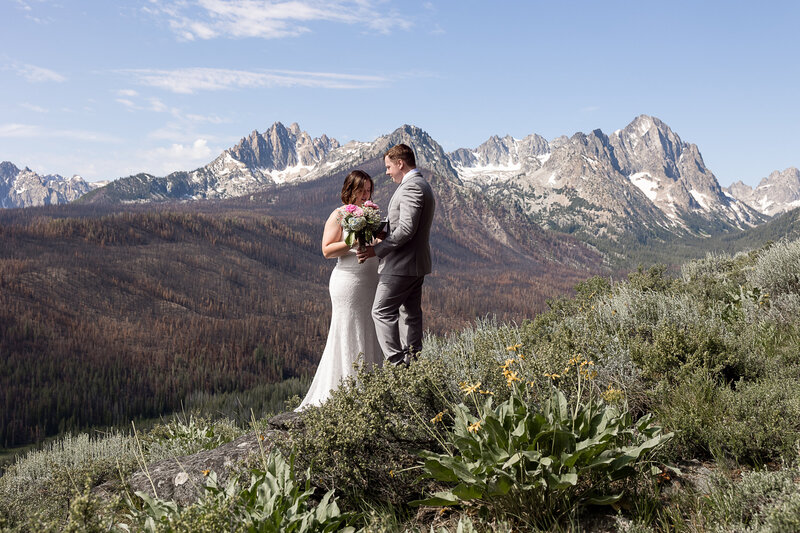 Couple standing on the edge of a cliff in Sawtooth Mountains sharing vows.