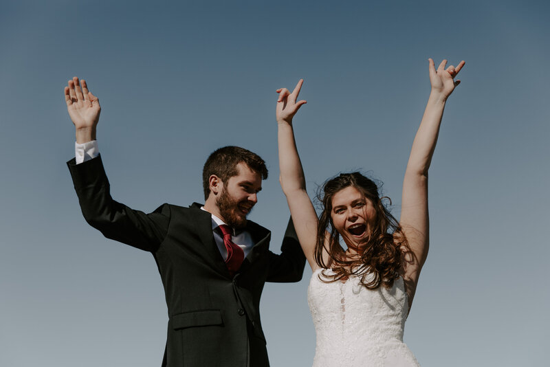 bride and groom standing with arms in the air while smiling