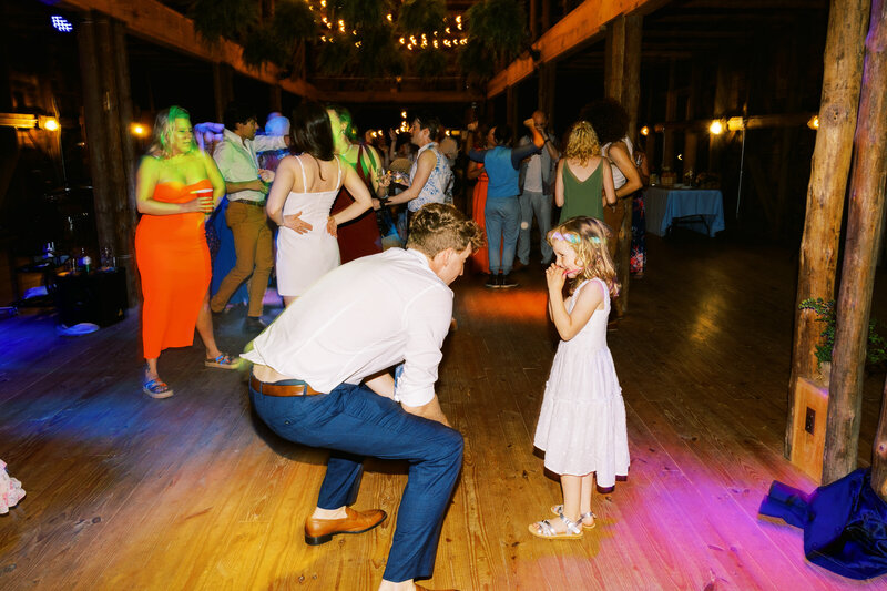 A candid moment with the Groom and flower girl during the wedding reception at scenic North Carolina venue by photographer My Sun and Stars Co.