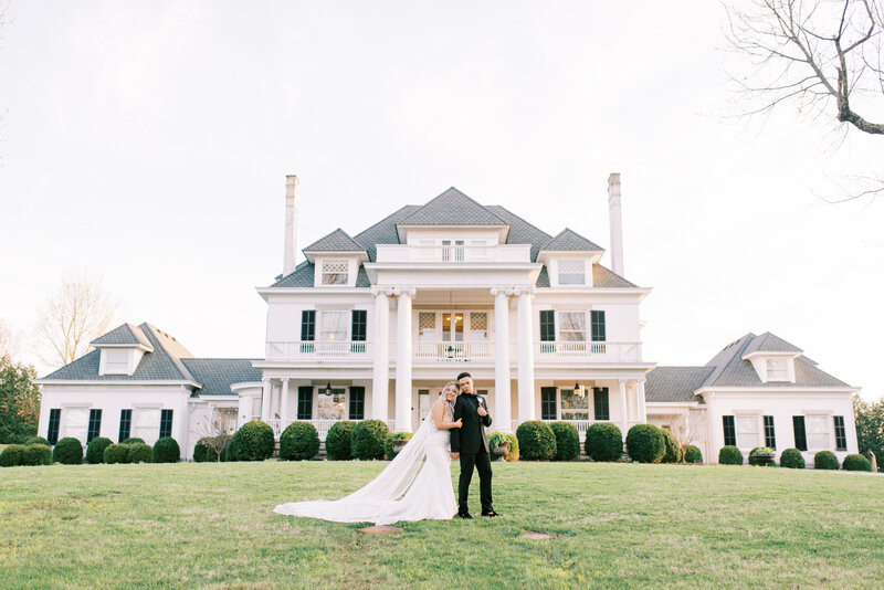 Bride and groom walking in front of a large mansion in kentucky