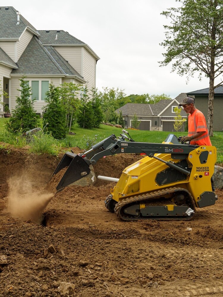 A landscaper using a skid steer to work on a Kansas City yard
