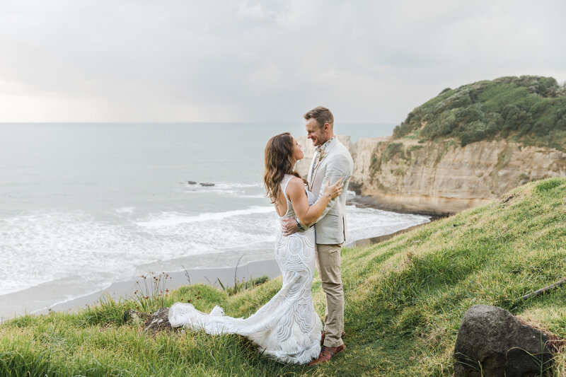 bride and groom on clifftop overlooking beach