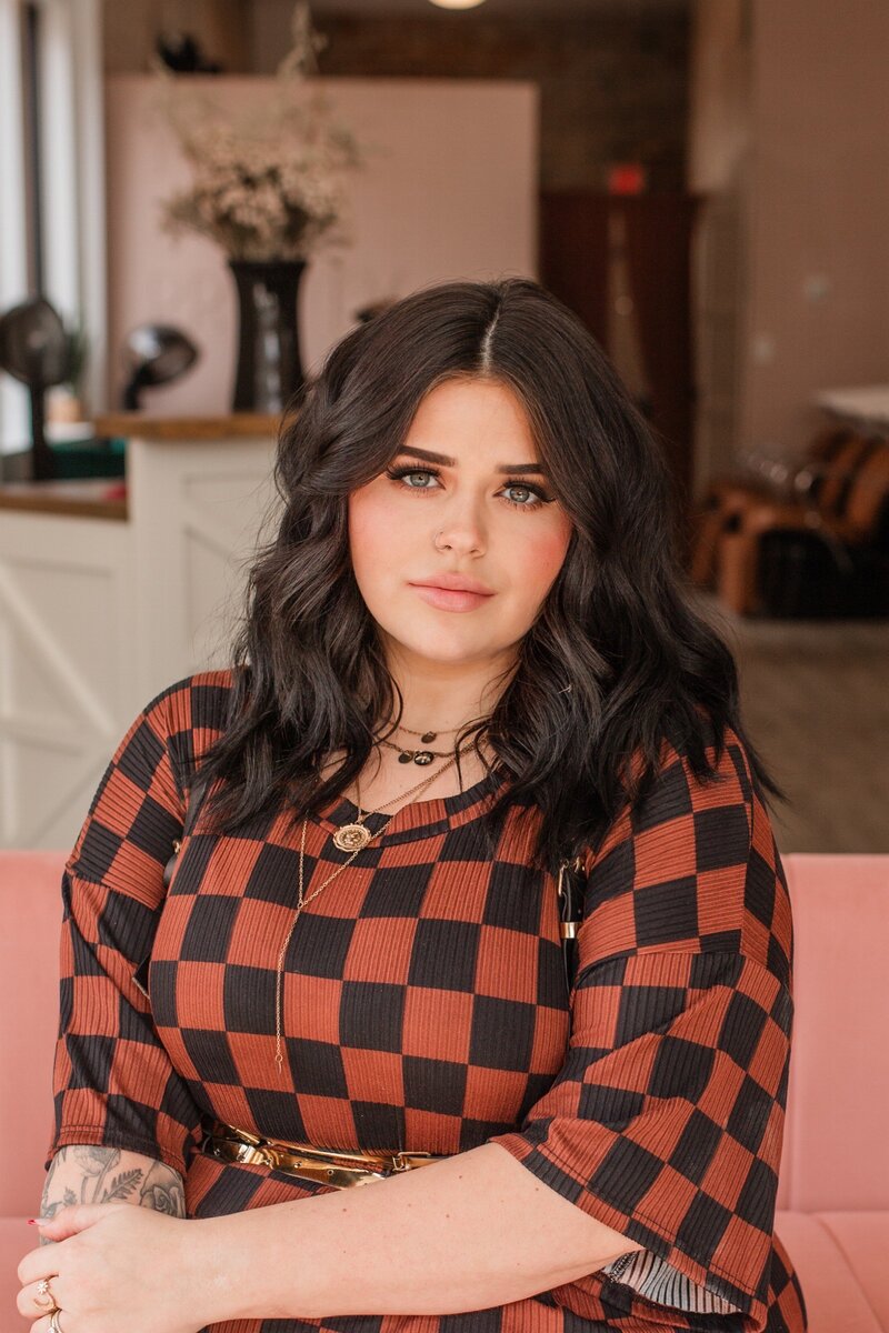 Hairstylist with shoulder-length dark hair, specializing in hair coloring and styling at The Vanity Hair Studio in Griffin, GA, known for vibrant hair transformations.