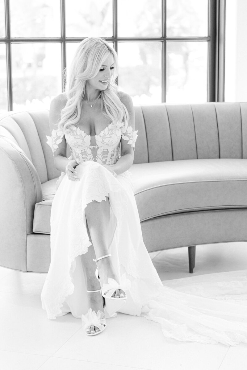 bride sits on a couch with her legs crossed at spanish hills club taken by magnolia west photography