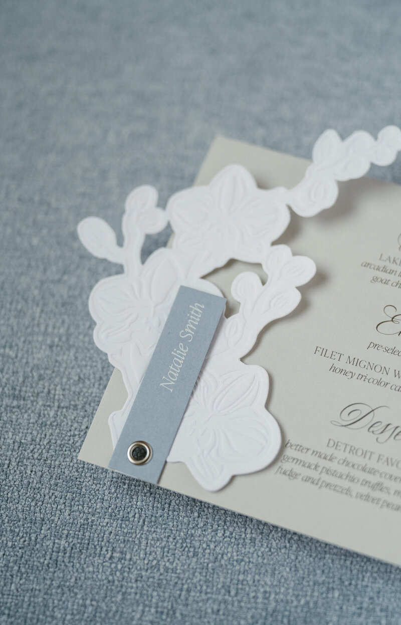 Alyssa Amez a custom wedding stationery and signage designer and business woman from Alyssa Amez Design showcasing a wedding dinner plate featuring her custom-designed menu  at her client's wedding venue