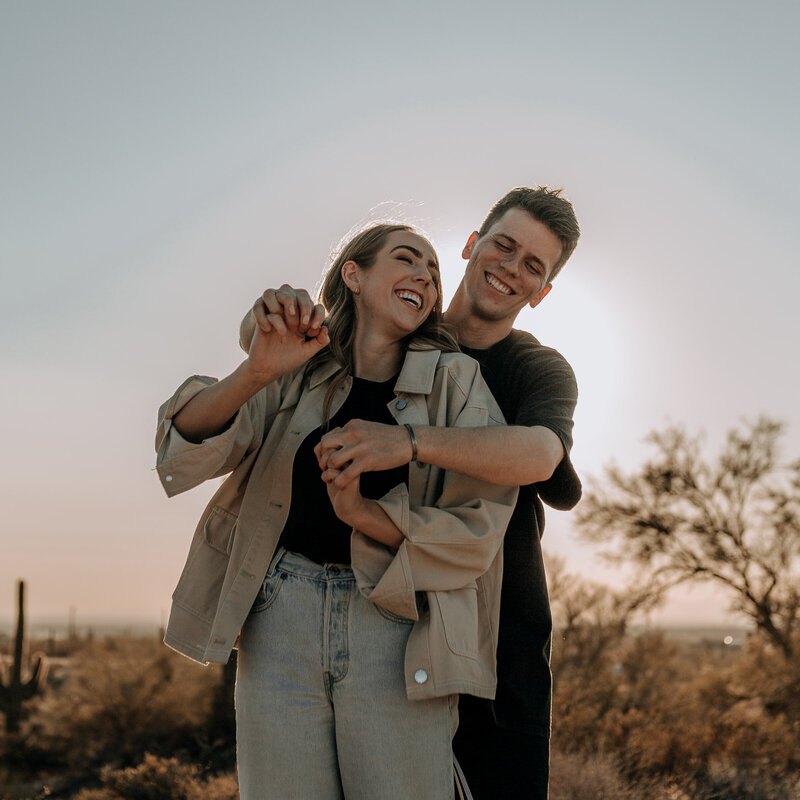 couple engagement session laughing and dancing in the desert