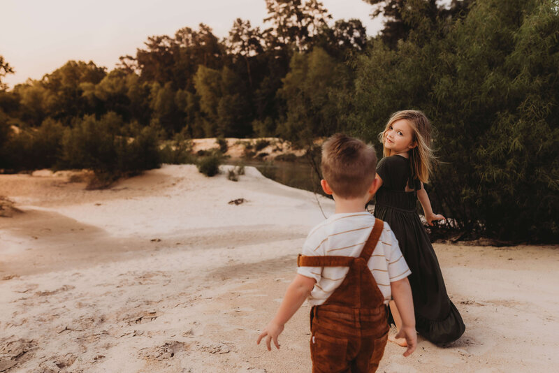 siblings running through the sand during a family session in The Woodlands, Texas