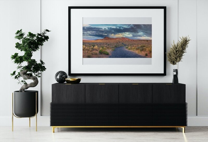 framed desert landscape on room wall with a black table situated in front