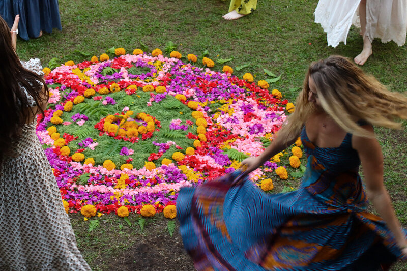 A group of women dancing and spinning around a vibrant colorful flower mandala, an example of Courtney's retreat photography