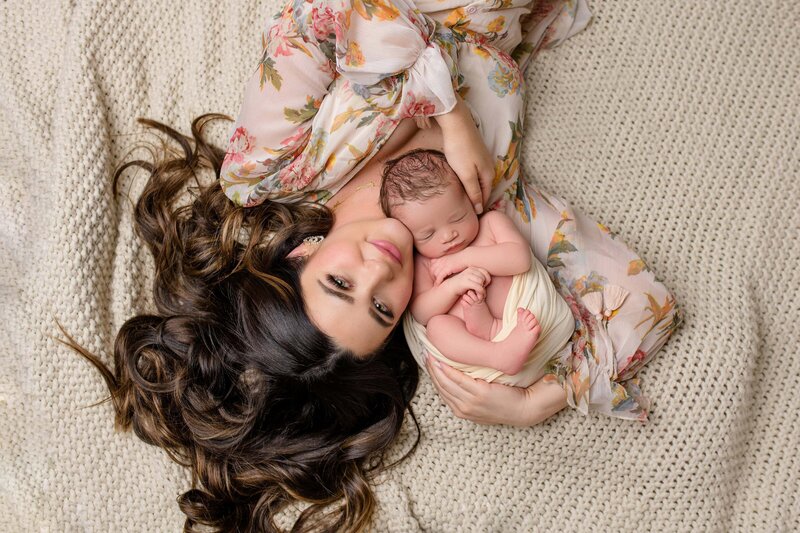 a new mother laying on her back cuddling her newborn son