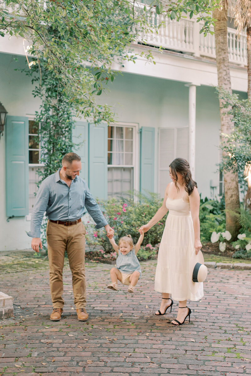 family swinging their baby in a brick courtyard in historic Charleston