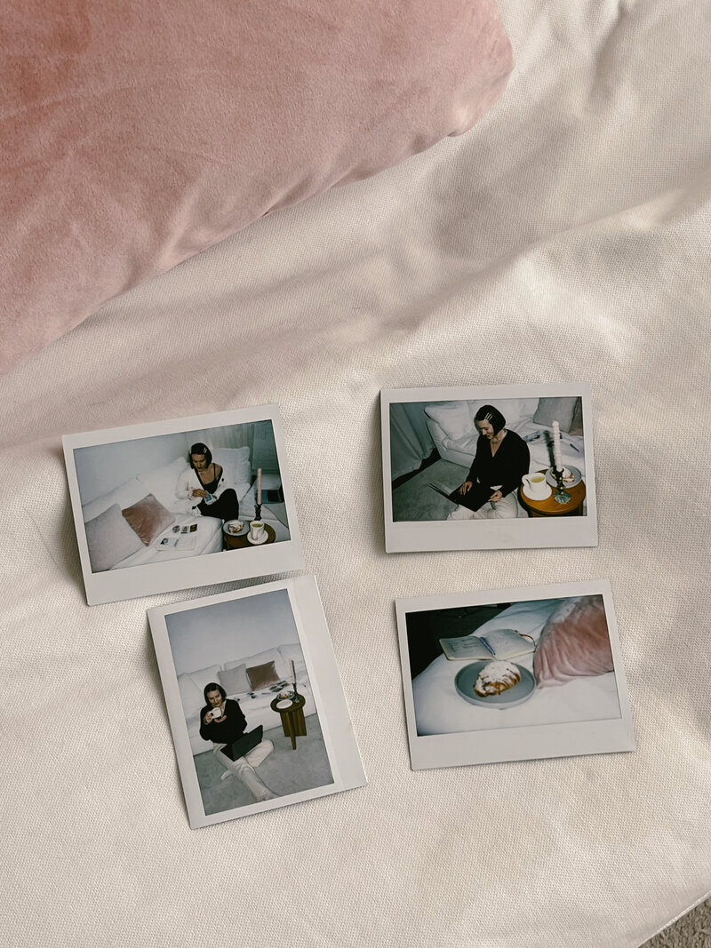 Flour polaroids laid out on a white couch show Margarita doing random copywriter things, like doing a tarot spread, sipping some matcha, typing away, with a croissant by her side.