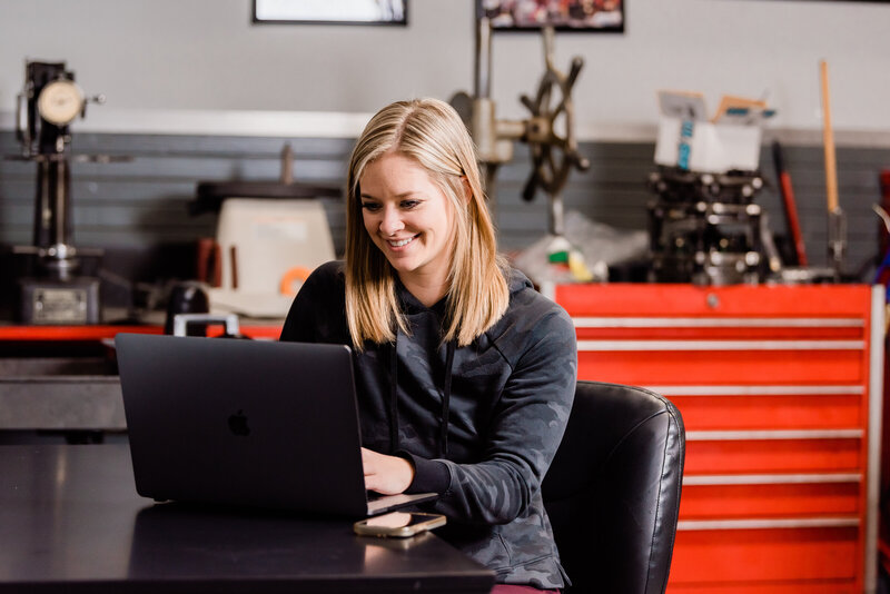 woman sitting at table smiling while working on laptop