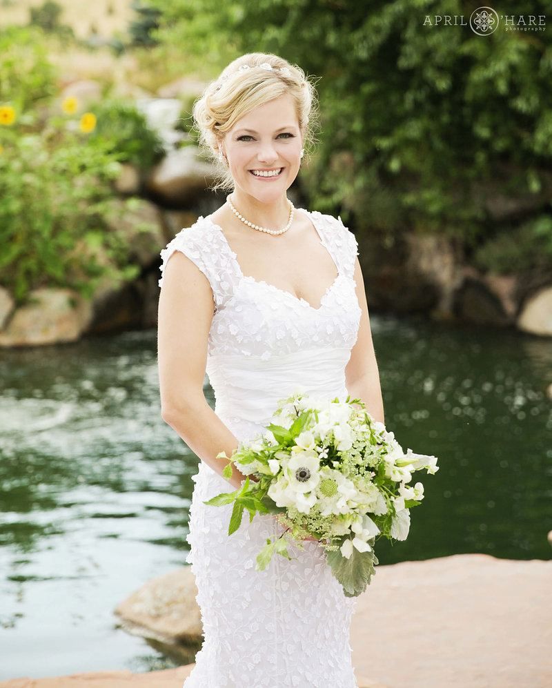 Beautiful bride holding her bouquet in front of the pond at Greenbriar Inn Boulder CO