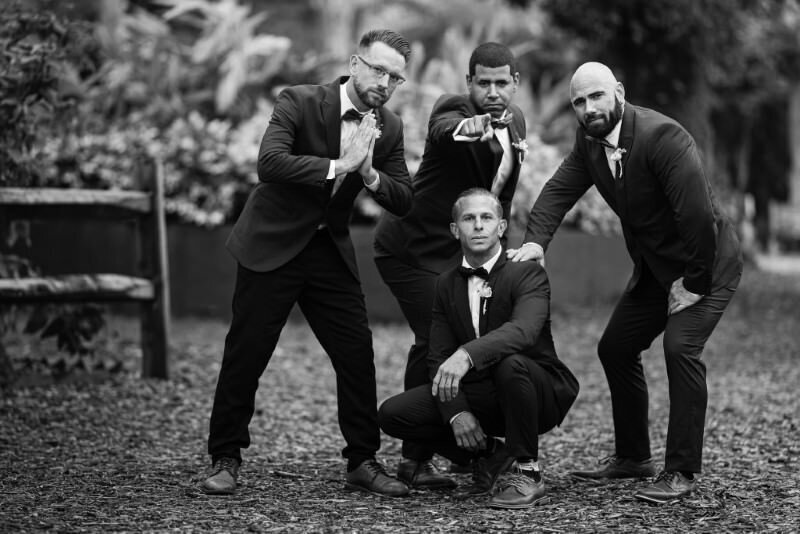 groom poses with his groomsman in a black and white photo