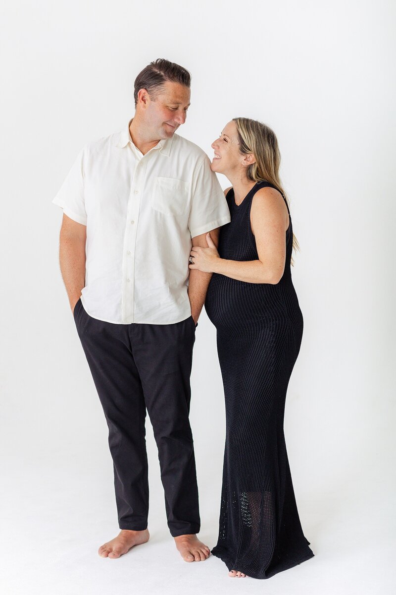 couple in modern black and white attire poses for maternity photos in Los Angeles studio