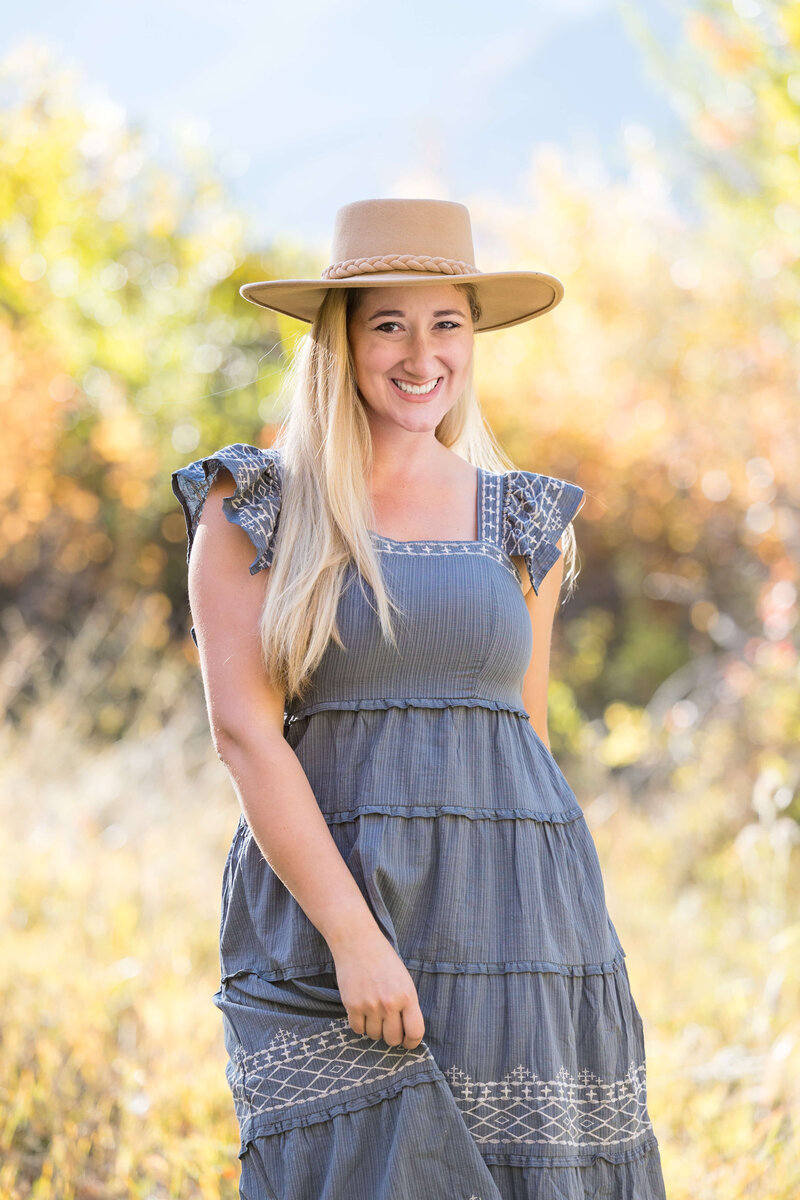 Award winning wedding and family photographer for Colorado Springs and all of Colorado Erin Winter smiling at camera and wearing a blue dress and hat