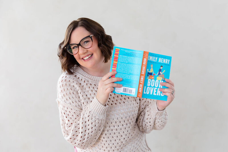 What Sara Reads owner Sara Gillis holding an open book and smiling