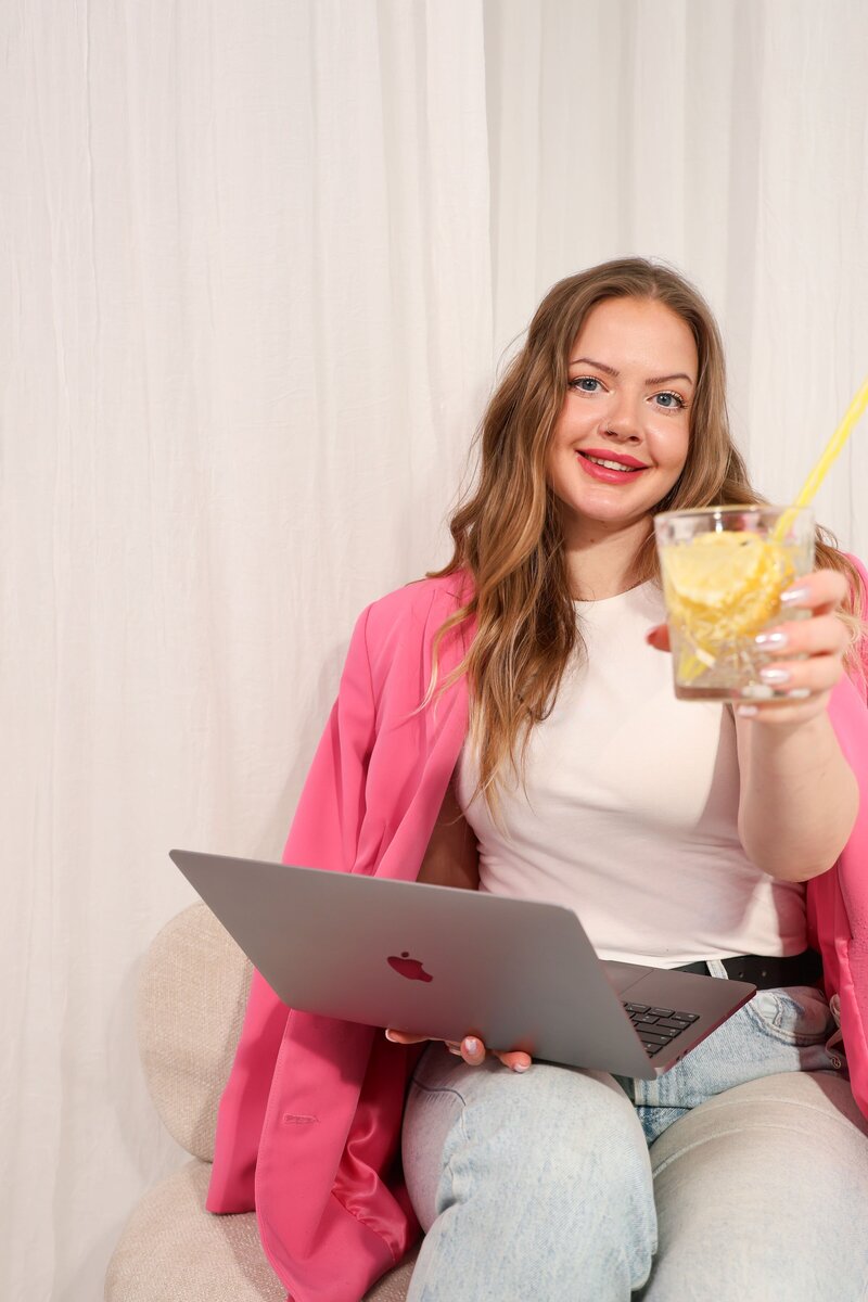 studiomaiju istuu tuolilla kädessään läppäri ja sitruunafantaa