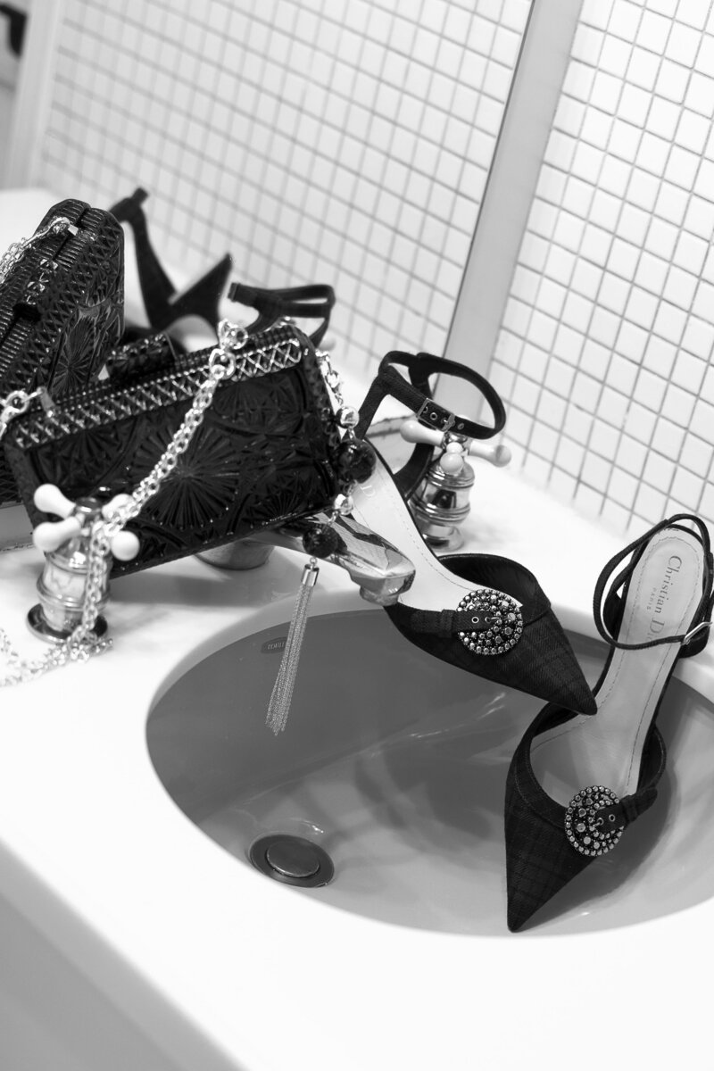 Handbag and heels hang about a vintage sink.