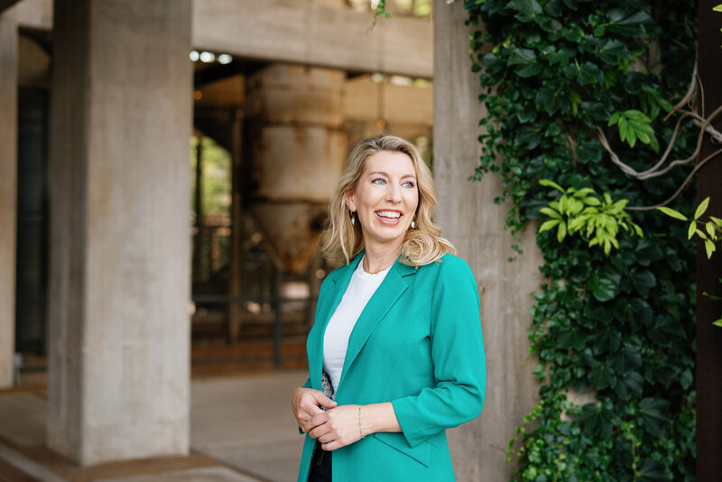 Amy lane in a turquoise blazer smiling off to the side