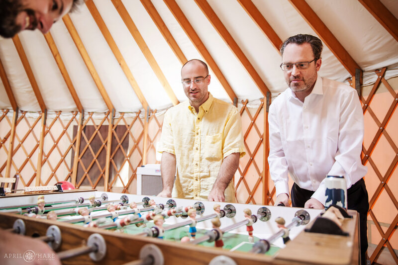 Groomsmen play foosball inside Yurt at Chatfield Farms Denver Botanic Gardens