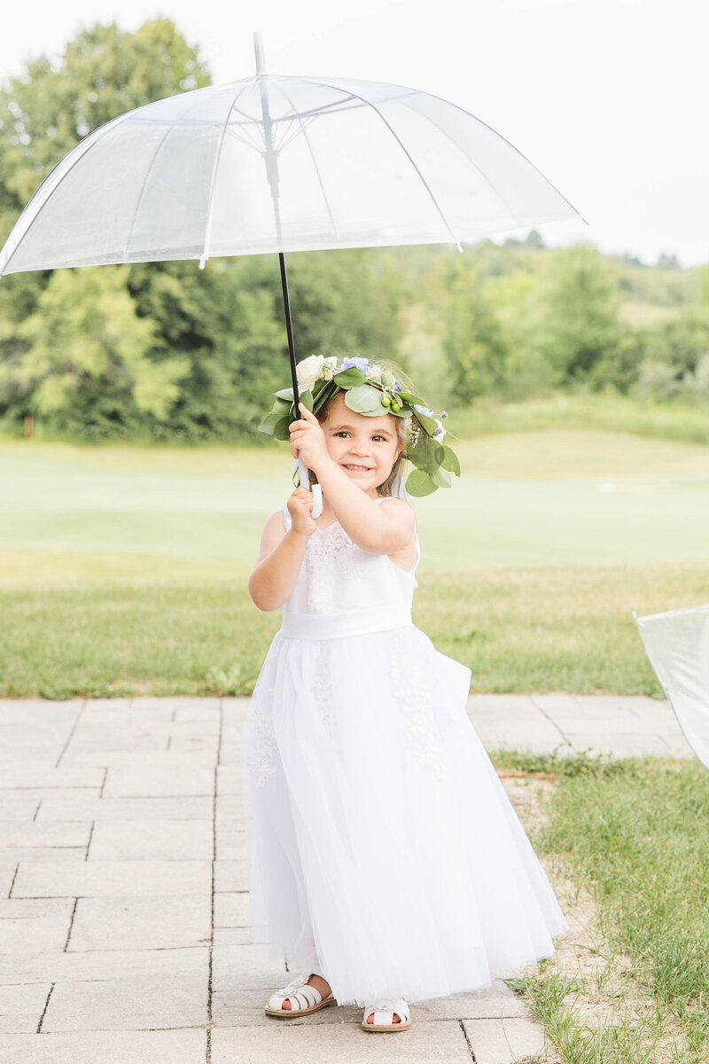 Flower girl twirling umbrella on wedding day.