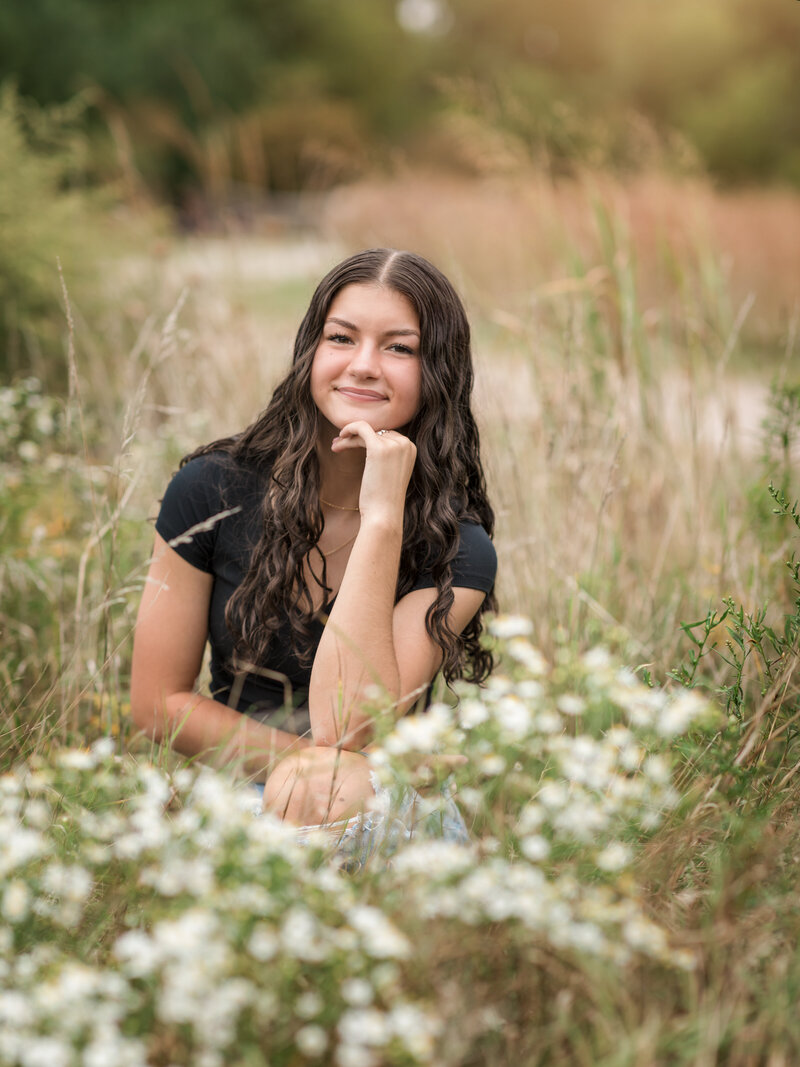 senior girl in black shirt sitting in flower field for senior photos Cleveland family photographer