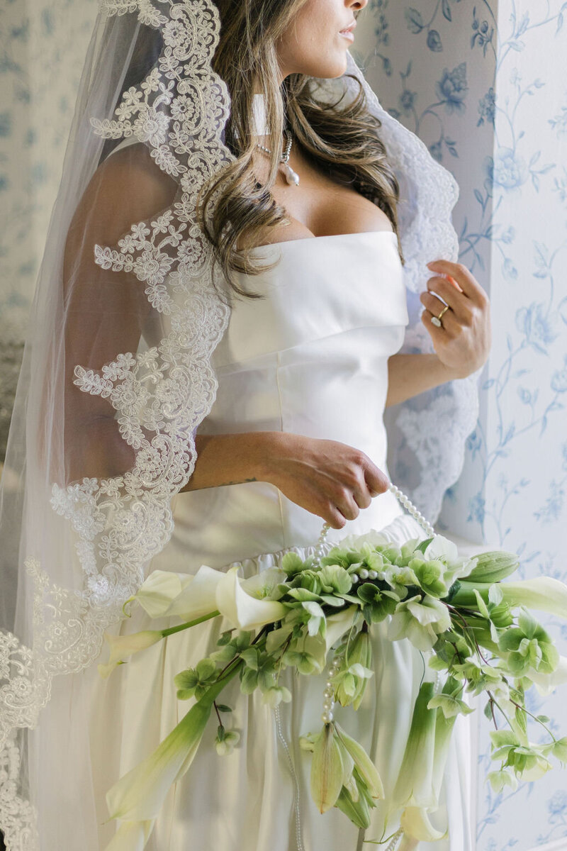 Bride holding an elegant modern bouquet while wearing a structured satin gown — editorial Colorado wedding portrait