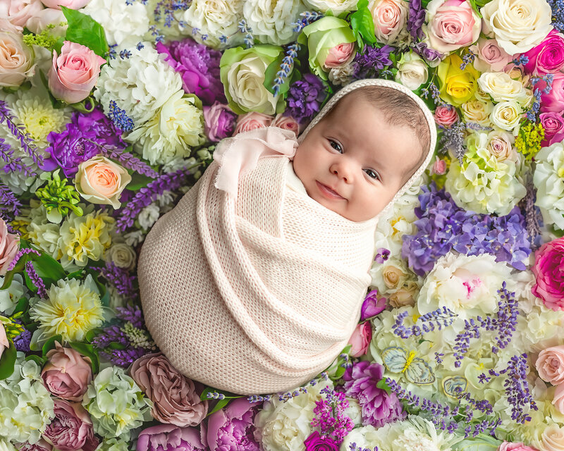 A radiant newborn portrait bursting with personality and petals—styled in soft floral tones.