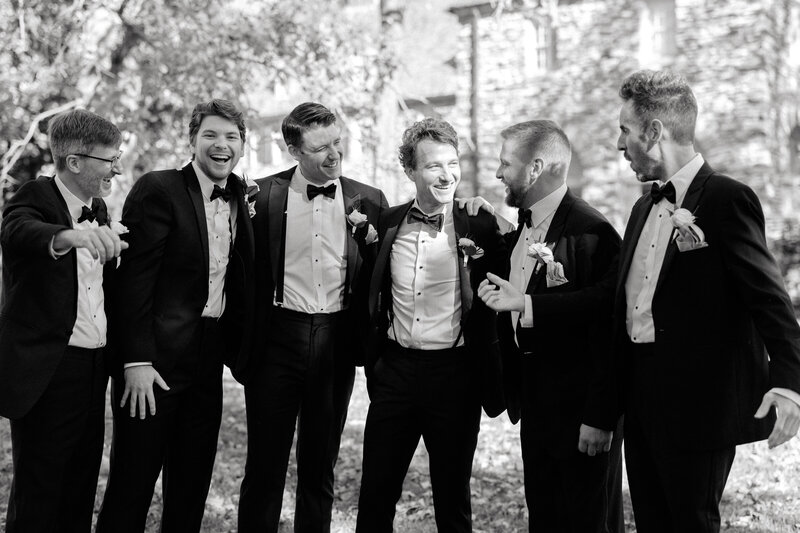 November wedding at Graylyn Estate, designed and planned by Charming Carolina — groom and groomsmen posing in black tuxedos outside the estate’s stone architecture.