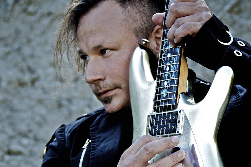 Musician portrait Kevin Estrella Pyramids on Mars closeup holding electric guitar to face against large rock