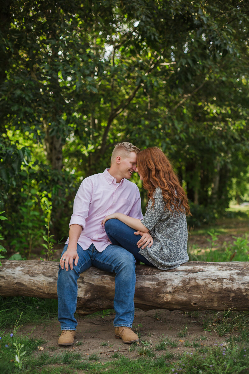 young couple sitting on log during Pigeon Forge engagement session