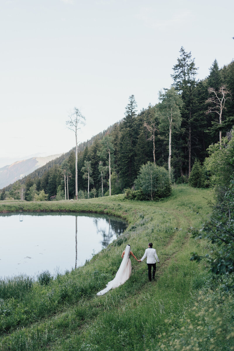 Bride and groom share a kiss in front of a mountain backdrop while  guests throw confetti.