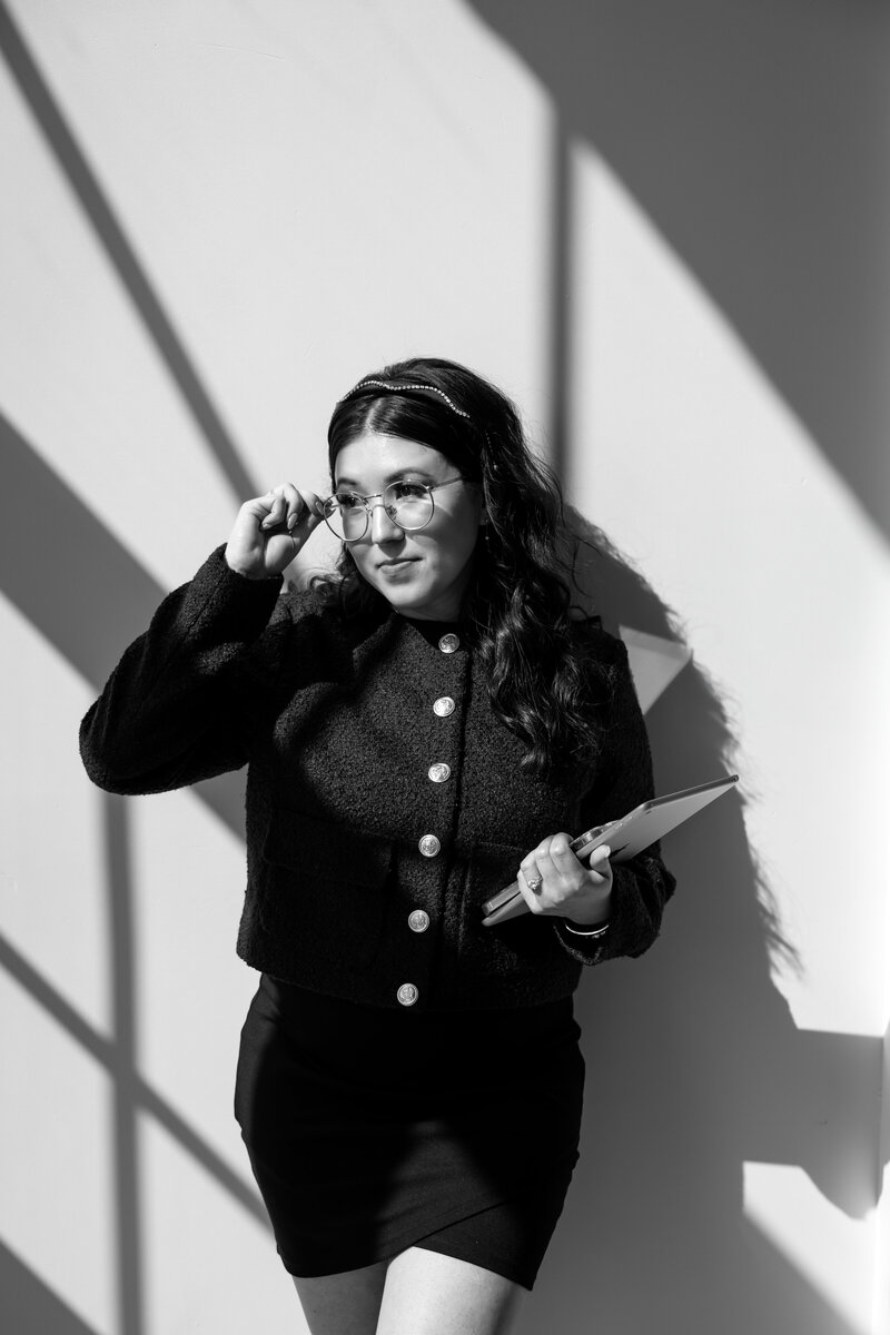 Shanté Gorman, founder of Sugarpunch Marketing®, a social media agency, wearing glasses and holding a tablet in black and white.