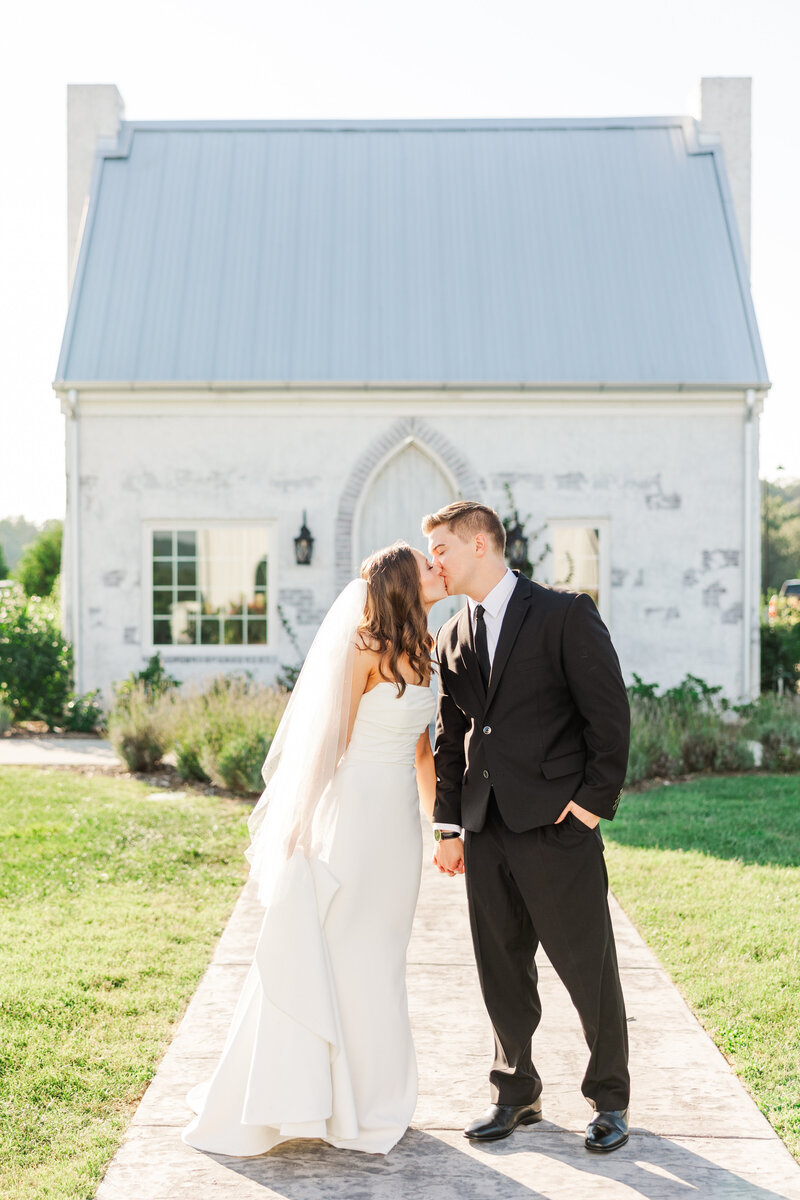 bride and groom kissing in front of a cottage