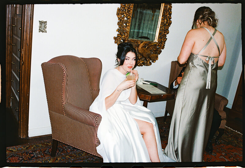 Bride signing marriage license in bridal suite with a cocktail, captured on flash film with vintage tones | editorial, luxury, documentary wedding photography on 35mm